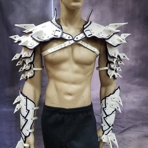 May include: White leather armor with blue accents and spikes. The armor includes shoulder pads and forearm guards.