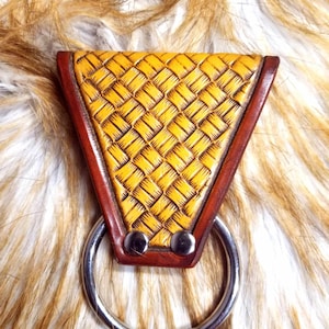 May include: A handcrafted leather keychain holder with a woven yellow design. The holder has a brown border and is attached to a silver metal ring. The keychain holder is secured with two silver rivets.