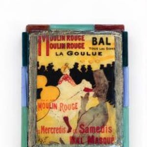 May include: A rectangular decorative plaque featuring a Moulin Rouge La Goulue poster print, framed by a border of multicolored glass tiles in shades of blue, green, and red. The print displays figures in a yellow and black setting.