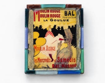 May include: A rectangular decorative tile featuring a Moulin Rouge La Goulue poster print, framed by a border of small, multi-colored glass tiles in shades of blue, green, and brown, with gold-toned metal accents surrounding the central image.
