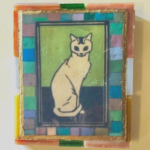 May include: A rectangular wall art piece featuring a central illustration of a seated cat against a green and dark blue background. The image is framed by a border of small, multi-colored glass tiles in shades of blue, green, and pink, with a gold-toned trim.