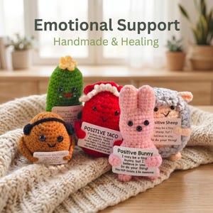May include: A selection of handmade crochet toys, including a green pickle, a red taco, a pink bunny, a grey sheep, and a brown potato. Each toy has a positive message attached. The text "Emotional Support" and "Handmade & Healing" are at the top.