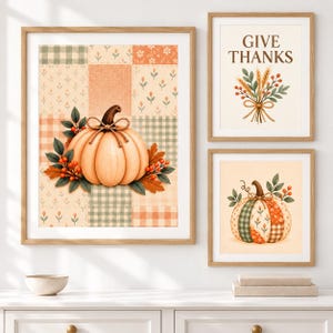 May include: Three framed wall art prints featuring autumn themes. The large vertical print shows a pumpkin on a patchwork background. The top right print displays the text GIVE THANKS with wheat and berries. The bottom right print shows a pumpkin.