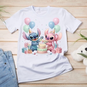 K&ouml;nnte beinhalten: Wei&szlig;es T-Shirt mit einer farbenfrohen Grafik von zwei Zeichentrickfiguren, einer blauen und einer rosa, die einen Geburtstag mit Kuchen, Luftballons und Geschenken feiern. Das Design beinhaltet Konfetti und Partyh&uuml;te.