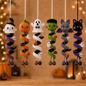 May include: Six hanging crochet ornaments featuring Halloween characters including a ghost with a hat, a pumpkin, a white ghost, a green monster, a grey bat, and a black cat. Each figure has a long, spiralling tail decorated with small charms.