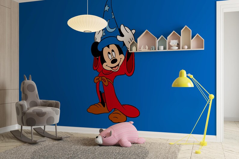 May include: A large wall decal of Mickey Mouse dressed as a sorcerer, featuring a blue hat with white moon and star patterns and a long red robe. The character is depicted with white gloves, standing against a solid blue wall in a room.