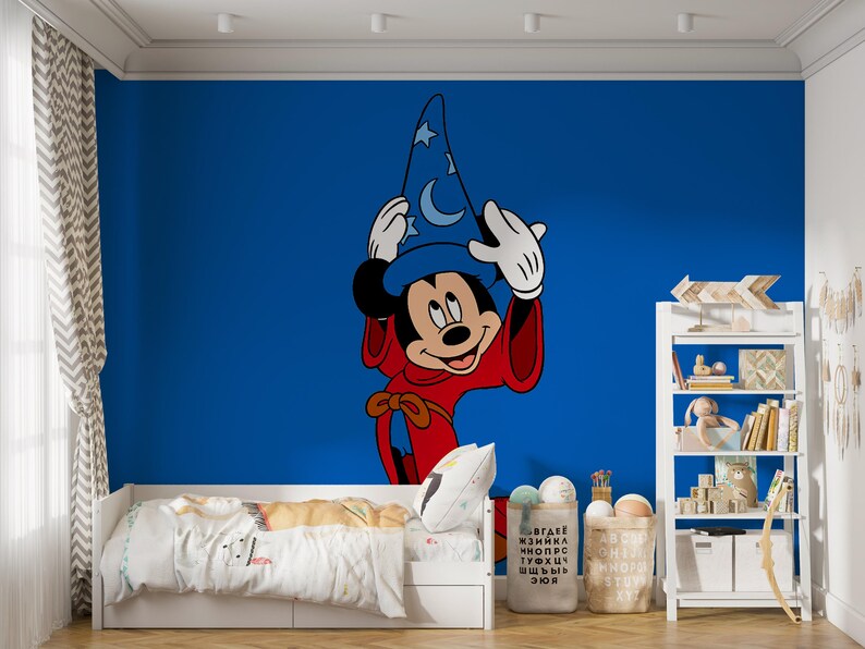 May include: A large wall decal featuring Mickey Mouse as a sorcerer, wearing a blue pointed hat with white moon and star patterns and a red robe. The character is positioned against a solid blue wall, centered above a white bed frame.