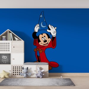 May include: A large wall decal of Mickey Mouse dressed as a sorcerer, wearing a blue hat with white stars and moons and a long red robe. The character is positioned on a solid blue wall next to a white modular storage unit with various compartments.