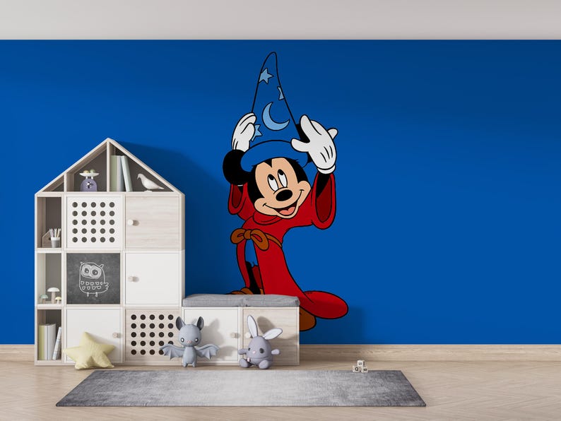 May include: A large wall decal of Mickey Mouse dressed as a sorcerer, wearing a blue hat with white stars and moons and a long red robe. The character is positioned on a solid blue wall next to a white modular storage unit with various compartments.