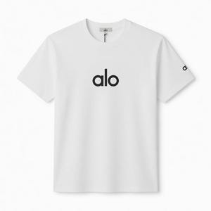 Puede incluir: Camiseta blanca de cuello redondo con la palabra "alo" impresa en negro en el pecho. El logotipo de la marca tambi&eacute;n est&aacute; en la manga. La camiseta tiene un dise&ntilde;o simple y minimalista.