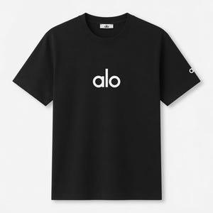 Op de afbeelding: Zwart T-shirt met ronde hals en het witte woord "alo" op de borst gedrukt. De merknaam "alo" staat ook in het wit op de bovenrug en op de linkermouw. Het T-shirt heeft korte mouwen.