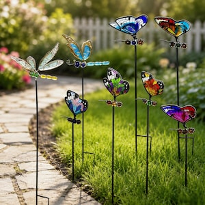 May include: A collection of seven garden stakes featuring colorful stained glass-style butterflies and a dragonfly. Each insect is mounted on a thin black metal rod, displaying vibrant patterns in blue, green, orange, purple, and red hues.