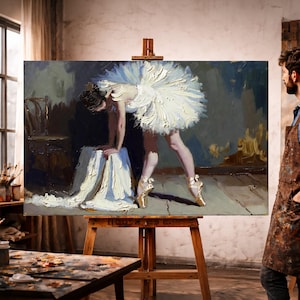 May include: Oil painting of a ballerina in a white tutu, leaning over a draped cloth. The artwork is displayed on a wooden easel in an artist's studio. The ballerina wears gold pointe shoes. The painting has a textured, impressionistic style.