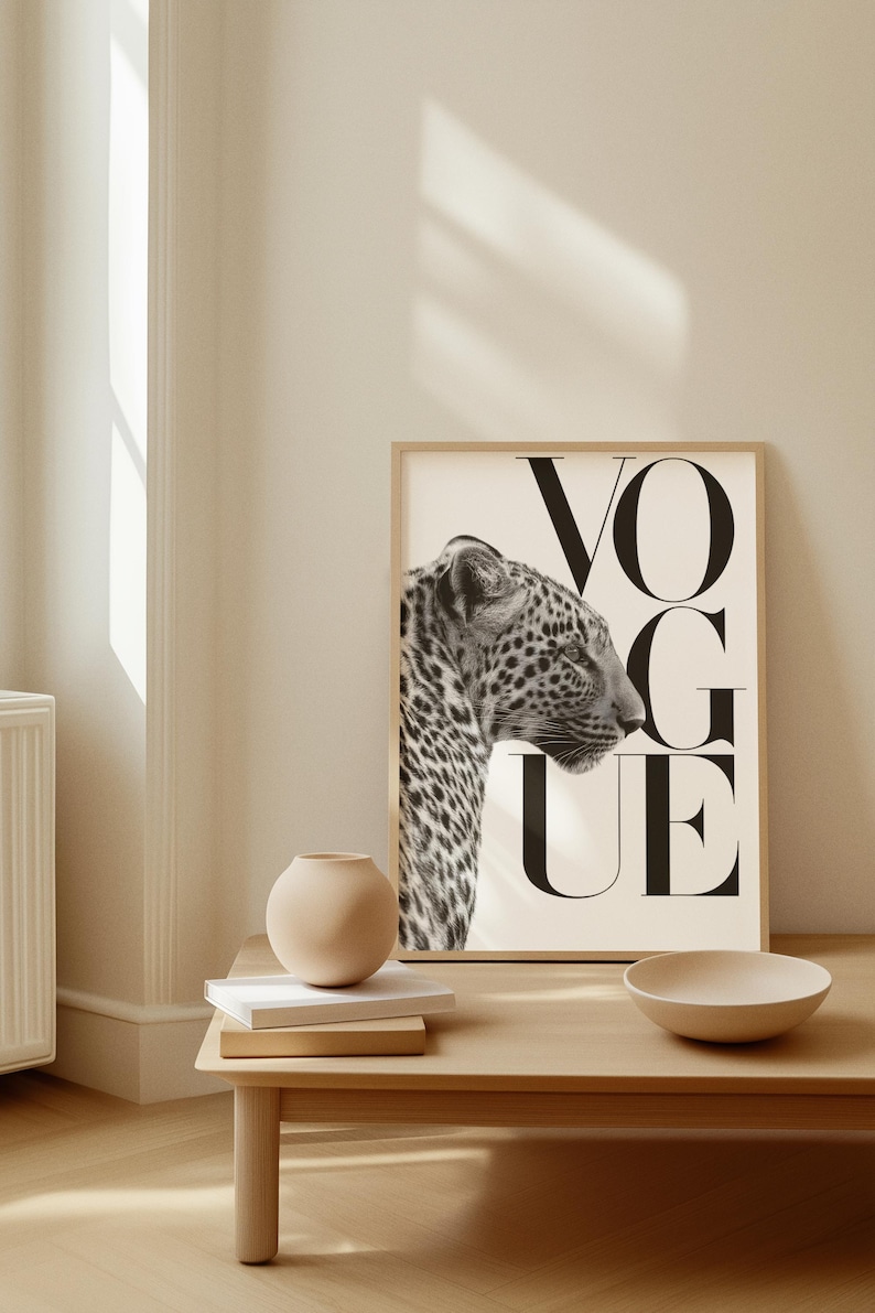 Pu&ograve; includere: Una stampa in bianco e nero incorniciata con il profilo di un leopardo e la parola "VOGUE" a lettere maiuscole. L'opera &egrave; esposta su una parete chiara, con un tavolo di legno in primo piano con un vaso, libri e una ciotola.