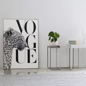 Pu&ograve; includere: Stampa in bianco e nero con un leopardo e la parola "VOGUE". Due comodini con una pianta, libri e una lampada. Un tappeto a righe bianche e nere in primo piano. Stanza con pareti bianche.