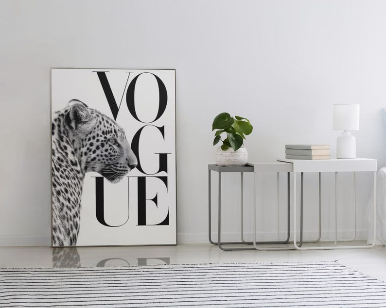 Pu&ograve; includere: Stampa in bianco e nero con un leopardo e la parola "VOGUE". Due comodini con una pianta, libri e una lampada. Un tappeto a righe bianche e nere in primo piano. Stanza con pareti bianche.