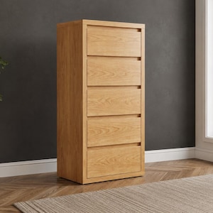Könnte beinhalten: Hohe Kommode aus hellem Holz mit fünf Schubladen. Das Möbelstück hat eine natürliche Holzfarbe und ein schlichtes, modernes Design. Es steht vor einer dunkelgrauen Wand und auf einem Holzboden.
