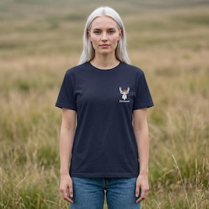 Könnte beinhalten: Ein dunkelblaues T-Shirt mit kurzen Ärmeln und einer kleinen weißen Grafik eines Hirschkopfes mit goldener Krone auf der linken Brust. Unter der Grafik ist das Wort Fireheart in weißer Schrift gedruckt. Das T-Shirt hat einen Rundhalsausschnitt.