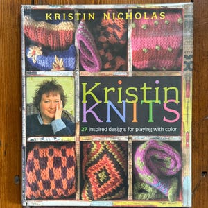 May include: A hardcover book titled Kristin Knits by Kristin Nicholas, featuring a grid layout of colorful knitted swatches and a photograph of the author. The cover text reads Kristin Nicholas, Kristin Knits, and 27 inspired designs for playing with color.