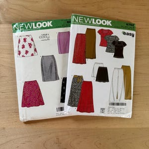 May include: Two New Look sewing pattern envelopes, 6822 and 6762, featuring illustrations of various skirts, tops, and pants. The white paper envelopes display garment designs in red, black, brown, and white, with text including New Look and easy.