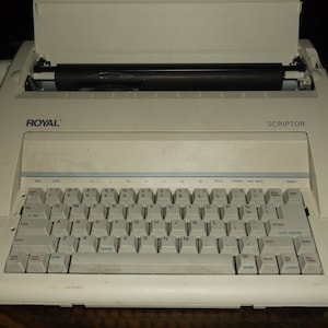 May include: A white Royal Scriptor electric typewriter with a black roller and a standard QWERTY keyboard.