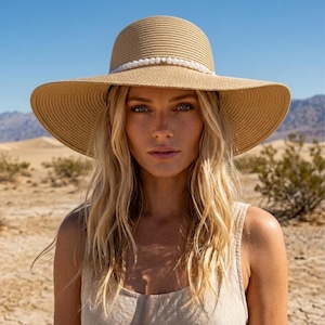 May include: A wide-brimmed tan straw hat featuring a rounded crown and a decorative band of small, white, spherical beads encircling the base of the crown. The hat is constructed from a woven material with a consistent, textured pattern throughout.