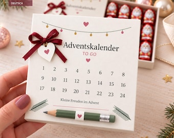 May include: A square white cardboard advent calendar box labeled Adventskalender TO GO with numbers 1 through 24, a dark red ribbon bow, a small heart charm, and a green pencil attached. The box contains small chocolate Santa Claus figures.