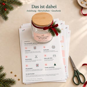 May include: A clear glass jar with a bamboo lid, a red velvet ribbon, and a small pine sprig. The label reads "Kleine Pausen im Advent". Beneath the jar are printed instruction sheets with the text "So entsteht dein Geschenk" and a pair of scissors.