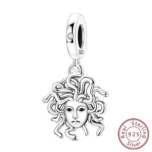 Op de afbeelding: Een zilveren bedel met een gedetailleerd Medusa-hoofd met slangenhaar. Het cilindrische oogje is gestempeld met 925 en bevat een kleine heldere steen. Het ontwerp is uitgevoerd in gepolijst sterling zilver met donkere geoxideerde accenten.