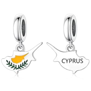 Op de afbeelding: Twee zilveren bedels in de vorm van de kaart van Cyprus. De ene bedel toont de geel-groene vlag van Cyprus, terwijl de andere de omtrek van het eiland laat zien met het woord CYPRUS in zwarte hoofdletters gedrukt op een witte achtergrond.