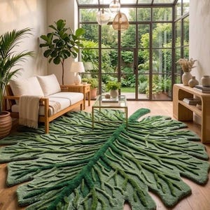 Puede incluir: Una gran alfombra verde con forma de hoja domina una sala de estar con un sofá de madera, una mesa de centro de cristal y grandes ventanales. El diseño de la alfombra presenta patrones de venas detallados, agregando textura e interés visual.