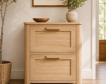 May include: A light-colored wooden cabinet with two drawers. The cabinet has a rectangular shape with a natural wood grain finish. The drawers have simple, horizontal handles. A wooden bowl and a vase with greenery sit on top.