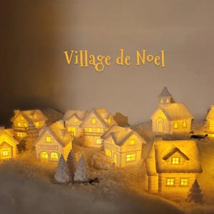 Può includere: Un villaggio natalizio in miniatura con diverse case e una chiesa in ceramica bianca, illuminate dall'interno da calde luci gialle, posizionate su una base di neve bianca testurizzata. Il testo Village de Noel è centrato in alto.