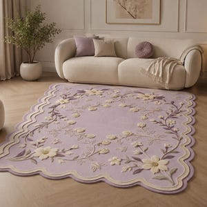 May include: A rectangular area rug in a soft lavender hue featuring a scalloped edge with cream and light purple borders. The surface displays a raised, tufted floral pattern with cream-colored flowers, green leaves, and small butterflies.