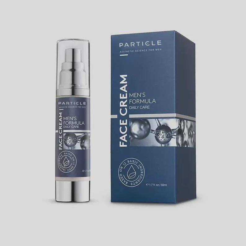 May include: A skincare product set featuring a pump bottle and a box. The bottle and box are navy blue with white text that reads "Particle Men's Formula Daily Care Face Cream." The box also displays the text "Aesthetic Science for Men."