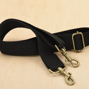 May include: A black canvas shoulder strap with two antique gold metal clasps.