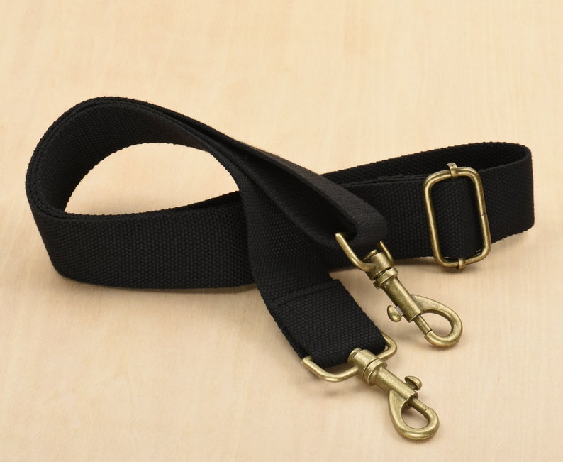 May include: A black canvas shoulder strap with two antique gold metal clasps.