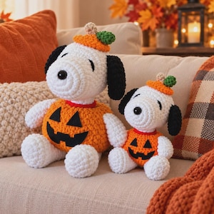 Puede incluir: Dos peluches de ganchillo hechos a mano con forma de perro blanco y orejas negras, cada uno con un traje naranja de calabaza con una cara de jack-o'-lantern negra y un pequeño tallo verde en la parte superior de la cabeza.