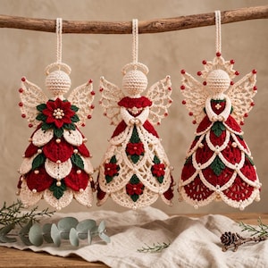 May include: Three crocheted angel ornaments hanging from a wooden branch. Each figure features cream, red, and green yarn with small white beads. The angels have detailed wings, halo accents, and layered skirts decorated with floral motifs.