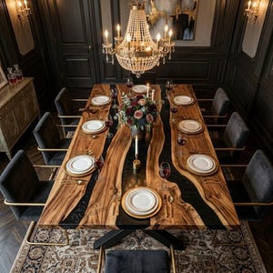 May include: A large dining table with a live edge wooden design and black resin inlay. The table is set with white plates, gold cutlery, and wine glasses. The room features a chandelier and dark grey chairs.