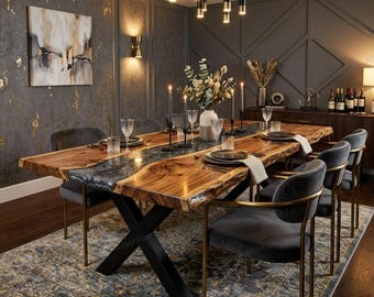 May include: A dining table featuring a natural live-edge wood slab surface with a central dark resin inlay, supported by a black metal X-shaped base. The table is surrounded by six grey upholstered chairs with gold-toned metal frames.