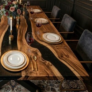May include: A wooden dining table with a black epoxy river feature, set for a meal. The table is adorned with white plates, gold cutlery, and wine glasses. A floral display and candles are present, with grey chairs arranged around it.