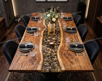 May include: A rectangular live edge wood dining table with a central glass-topped channel filled with smooth river stones. The table features a natural wood grain finish, black metal legs, and is set with six dark grey chairs, plates, and glasses.