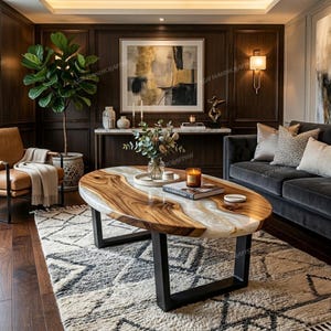 Op de afbeelding: Ovale houten salontafel met een lichtgekleurd epoxyhars middenstuk en zwarte metalen poten. De houtnerf is zichtbaar. De tafel staat in een woonkamer met een patroonkleed en donkere houten lambrisering.