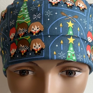 May include: A blue scrub hat with a Christmas-themed pattern featuring Harry Potter characters and Christmas trees.