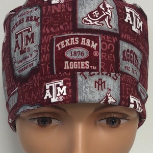 May include: A maroon scrub hat with a repeating pattern of the Texas A&M logo, the words "Texas A&M", "Aggies", and "1876", and a stylized wolf.