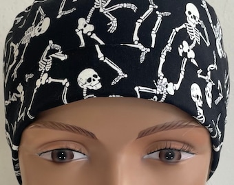 Könnte beinhalten: Schwarze OP-Mütze mit einem weißen Skelettmuster. Die Mütze ist aus einem weichen, bequemen Stoff gefertigt und perfekt für medizinisches Personal.