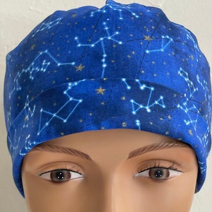 May include: A blue scrub hat with a constellation pattern in gold and white. The hat is made of a soft, comfortable fabric and is perfect for healthcare professionals.