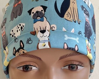 Könnte beinhalten: Eine blaue OP-Mütze mit einem Muster aus verschiedenen Hunderassen. Die Mütze ist aus einem weichen, bequemen Stoff gefertigt und perfekt für medizinisches Personal.