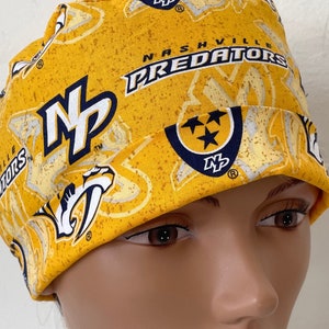 May include: Yellow and blue patterned scrub hat with the text "Nashville Predators" and the logo "NP".
